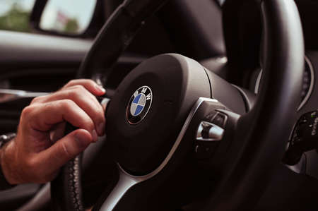 Bologna, Italy, May 15, 2019, the city of Bologna. BMW car steering wheel. Male hand in the frameのeditorial素材