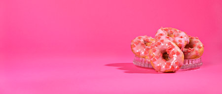 Sweet gift on Valentines Day, Pink donuts with hearts on a bright background. Festive pastries. Long format banner. Copy space. High quality photoの写真素材