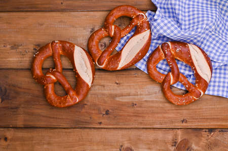 Bavarian pretzel decorated with a blue and white cloth on a rustic wooden board - Munich...