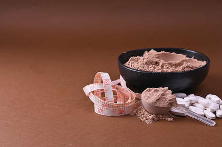 Sports nutrition on a black background. Protein and dietary supplements in powder and in tablets....