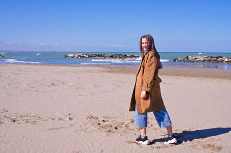 A person standing in front of a beach. Beautiful young girl walks along the seashore. The...