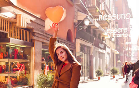 The concept of Valentines Day and Womens Day. Young Girl with a balloon in the street in the...