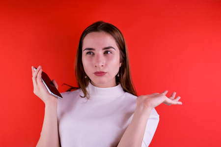 Young girl talking on a smartphone on a red background. Copy space.の写真素材