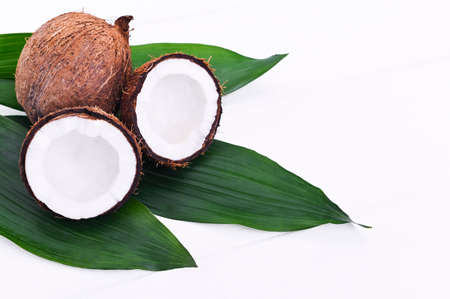 Coconuts and palm leaves on a white wooden background. Natural cosmetics and healthy nutrition from...