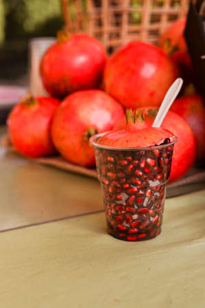 A large glass with peeled pomegranate. Ripe pomegranates in a basket at the market. Seasonal fruitsの写真素材