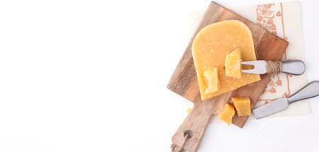 Parmesan cheese, on a wooden board and on a white background a knife for cheese. Traditional food....