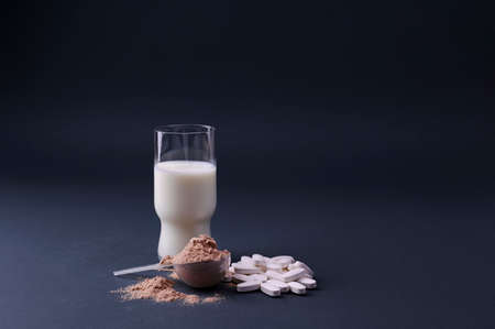 Pills, milk and Scoop of chocolate whey protein in a black bowl. The concept of healthy eating and vitaminsの写真素材