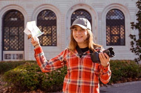 A girl with a card and a camera is having fun discoveries. Woman traveling and taking pictures...