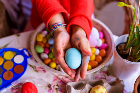 Little girl holding a bright colored Easter egg in her hands. Happy Easter Sunday celebration. Copy spaceの写真素材