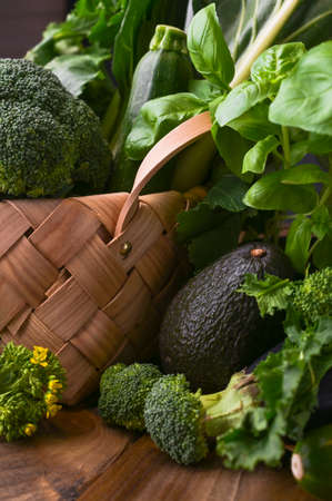 basket with fresh green vegetables on a wooden background. Avocados, broccoli, Cime di rapa other greens. Free space for text. Copy space.の写真素材