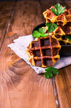 Lush belgian waffles with vegetables and herbs on a wooden table. The concept of a healthy diet and...