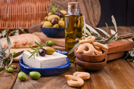 Greek cheese with olives and italian and ITALIAN CRACKERS or TARALLI . Fresh olive branches, olive oil in a bottle with traditional Italian snacks. Copy spaceの写真素材