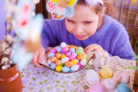 Easter. Little girl with colored eggs in her hands and chocolate colored eggs. Happy Easter holiday...