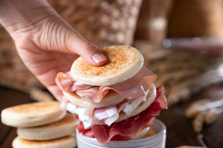 tigelle or crescentine homemade, con prosciutto, salame, stracciatella liquida. Italian food typical of the area of Modena, Emilia-Romagna. Thin round breads stuffed with prosciutto.の写真素材