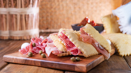 Crescentina. Food of Emilia Romagna region, deep fried bread gnocco fritto or crescentina. Starter or aperitif in Italy. Creshantina with prosciutto crudo, mortadella, Milanese salami, capers, cheeseの写真素材