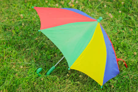 A colorful children's Umbrella on the green Lawn. The concept of a happy childhood. International Children`s Dayの写真素材