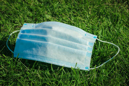 Flu epidemic, self-isolation and coronavirus protection concept. Medical face mask in the grass....