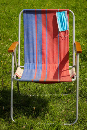 Blue face Mask on the handle of the Deckchair. Concept of social distance. Coronavirus Quarantine...