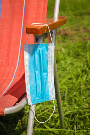 Blue face Mask on the handle of the Deckchair. Concept of social distance. Coronavirus Quarantine...