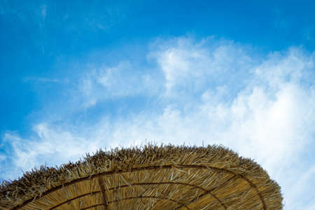 Straw beach Umbrella and bright Sky. Vacation holidays relaxing concept.