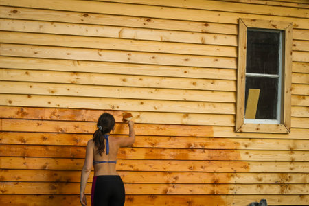A Girl paints a wooden wall of orange paint. Idea of repair.の写真素材