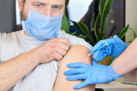 Hands of doctor injecting  virus   vaccine in vaccine syringe to arm muscle of caucasian man for   immunization.の写真素材