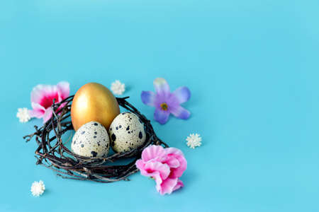 Golden Easter eggs in a nest on a blue background with space. Easter decoration, colored eggs in a...