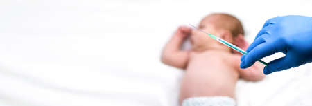 Pediatrician vaccinating newborn baby. Vaccine, Vaccination for infant child Soft focus Syringe in hands of a nurse and blurred background of infant baby on white. Banner horizontal.の写真素材