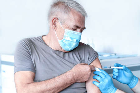 Elderly Man in Face Mask getting  Vaccine. Doctor giving Injection to senior Man at Hospital.の写真素材