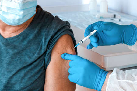 Doctor Vaccinating Senior Man In Clinic. Elderly People Vaccination. Doctor Giving   Vaccine Injection to Mature Man In Face Mask. Protection of Senior Patient. Old Man in Hospitalの写真素材