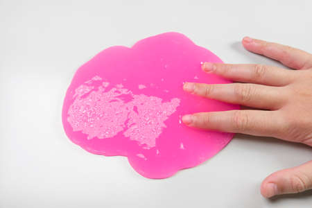 Playing with textured slime with bubbles, stretching the gooey substance. Female teen hand holding...