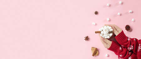 Winter drink, white mug with marshmallows in female hands in knitted Christmas Sweater on pink background. Top view, Flat Lay. New Year, Christmas traditional food. Festive decor, celebration Xmasの写真素材