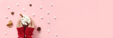 Winter drink, white mug with marshmallows in female hands in knitted Christmas Sweater on pink...