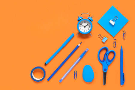 Back to school, business office education concept. Assortment of blue supplies, crayons, clock, pens on a table. Copy space background, top view flat lay overhead. Blue and Orange colors.の写真素材