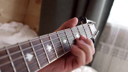 Music instrument. Musician plays and picks chords. Man plays acoustic guitar, clamps the strings...