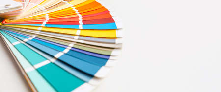 Color guide close up. Assortment of colors for design. Colors palette fan on white concrete wall...