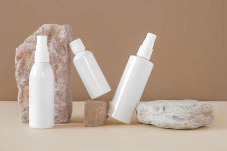 White blank cosmetic bottles, dried herbs on stone podiums. Natural skin care SPA beauty product design. Mineral Organic Cosmetics Mock-Up. Beige background. face and body treatment. front view.の写真素材