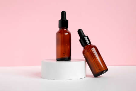Amber glass dropper cosmetic bottle, white podium. Natural skin care SPA beauty product design....