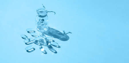 Pills and glass pill bottle on yellow background. Big golden tablets. Omega 3 capsules. Close up, top view. health care concept. Healthy every day fatty acids nutritional supplement dosage. flat lay.の写真素材
