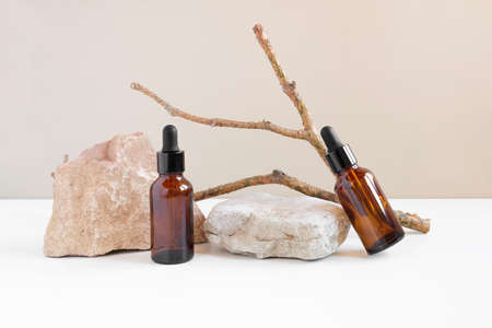Dark amber glass bottle standing on stone. Natural skin care SPA beauty product design. Mineral organic oil cosmetics on beige background. mockup. Oily pipette. face and body treatment. front view.の写真素材