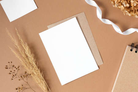 Blank greeting card, invitation mockup. Dry grass, pampas plant on beige table background. Flat lay,...