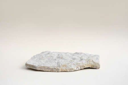 Stone Podium for promotion on beige Background. natural pedestal. One stone podium. beauty product mockup. scene to show products. Show case, display case. Front view, soft shadow.の写真素材