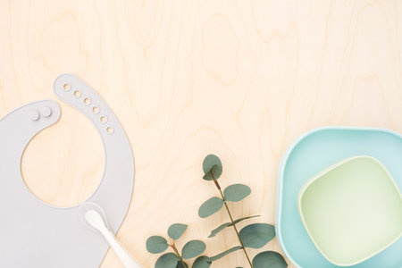 Baby accessories and tableware for food on beige background. First feeding for kids concept. Flat...