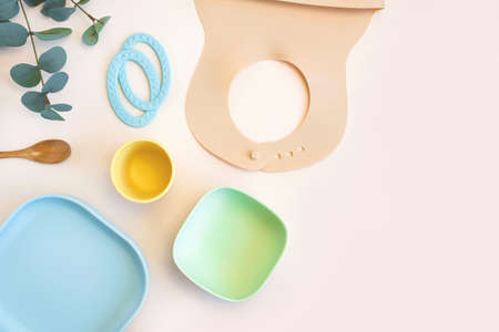 Baby accessories and tableware for food on beige background. First feeding for kids concept. Flat...