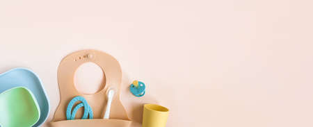 Baby accessories and tableware for food on beige background. First food for kids concept. Flat lay,...