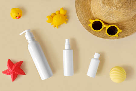 Sunscreen lotion tube on neutral background. Plastic bottle of sun protection and kids sunglasses...