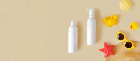 Sunscreen lotion tube on neutral background. Plastic bottle of sun protection and kids sunglasses and sandbox toys on beige table. Children's skin care concept. Sunscreen for kids. baby cosmetic.の写真素材