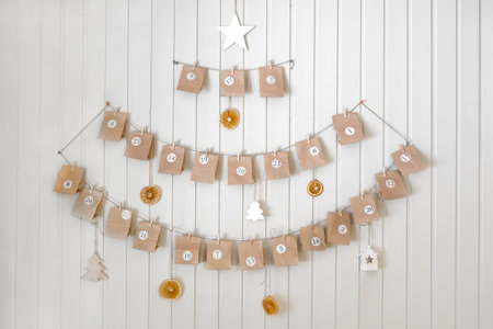 advent calendar. Small handmade paper gifts hanging on the background of wooden wall, close up. Christmas Calendar, gift for children. DIY. Sustainable Christmas. Celebrating at home, childhood.の写真素材