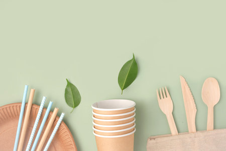 Eco - Friendly Tableware on Green Background. top view. Plastic free Set of Brown Paper Utensil. Street Food Recyclable Packaging. Zero waste Paperware. mockup. Disposable Take out Cup, wooden cutleryの写真素材