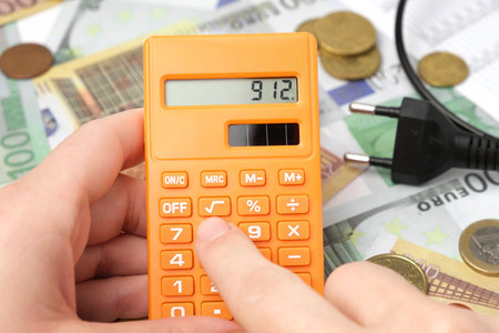 Person Counting and Calculate Cost Money of Electricity and Heating Bill. Electric Cap, Light Bulb and Euro Banknotes on the Background. Increase in the Cost of Electricity. price hike. energy crisisの写真素材